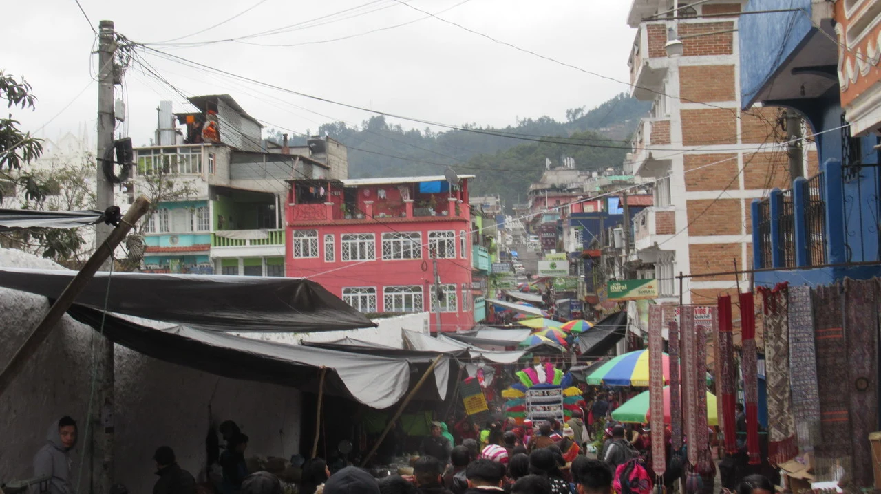 Una scena di strada affollata in un mercato colorato in una città collinare.
