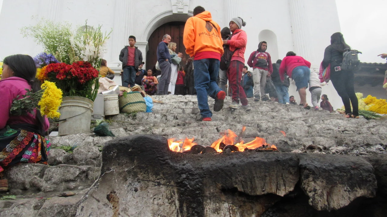Mercato di Chichicastenango con persone e fuoco in primo piano.