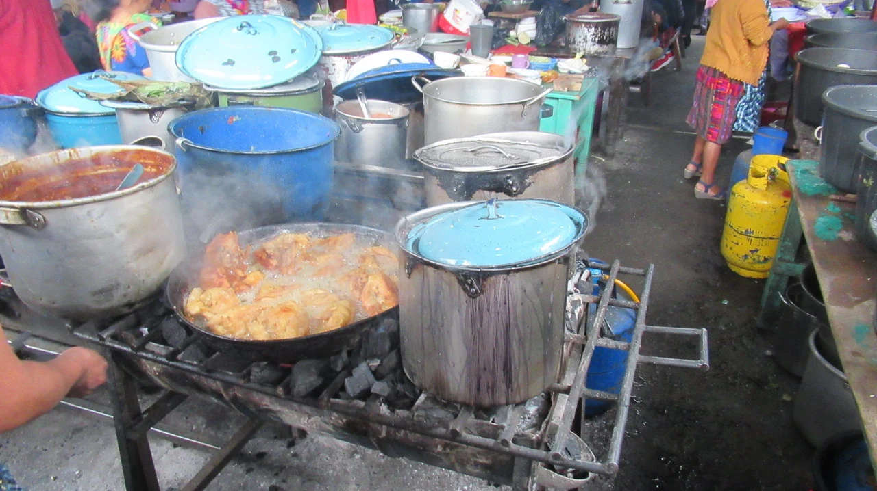 Mercato di Chichicastenango con cibo cucinato su griglie da strada.