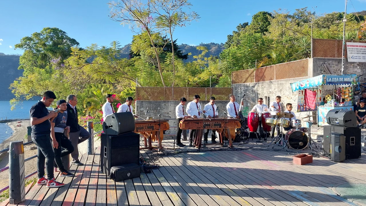 Un gruppo musicale suona strumenti all'aperto con vista sul lago.