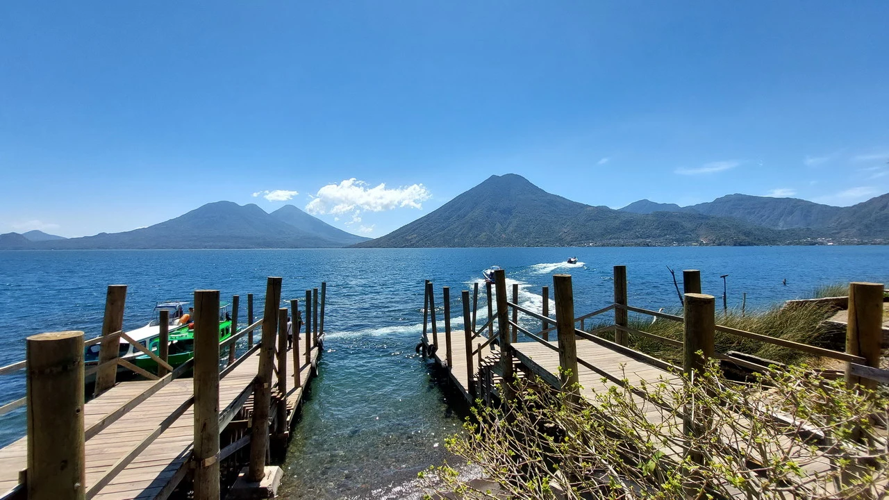 Vista panoramica di montagne che si riflettono sull'acqua con banchine in legno in primo piano.