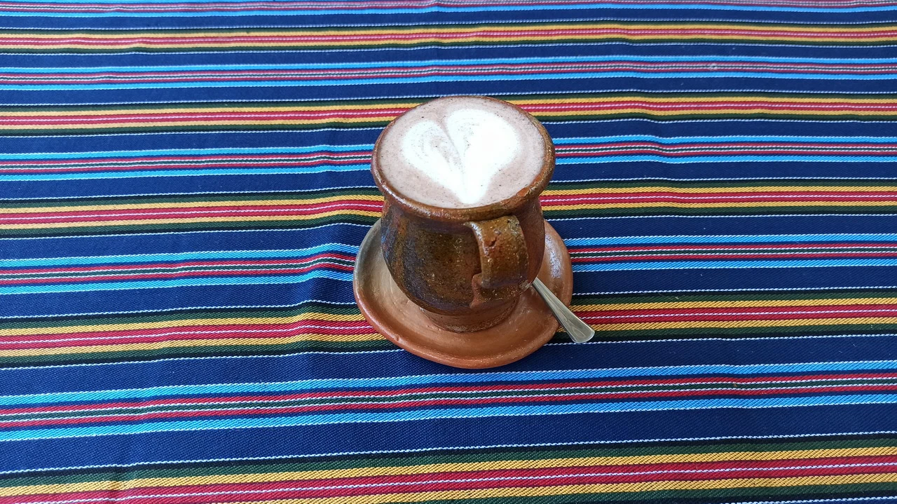 Una tazza di caffè è posta su un panno a strisce colorate.