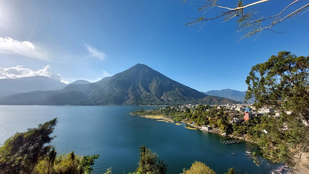 Catene montuose boscose si affacciano su un lago sotto un cielo azzurro.