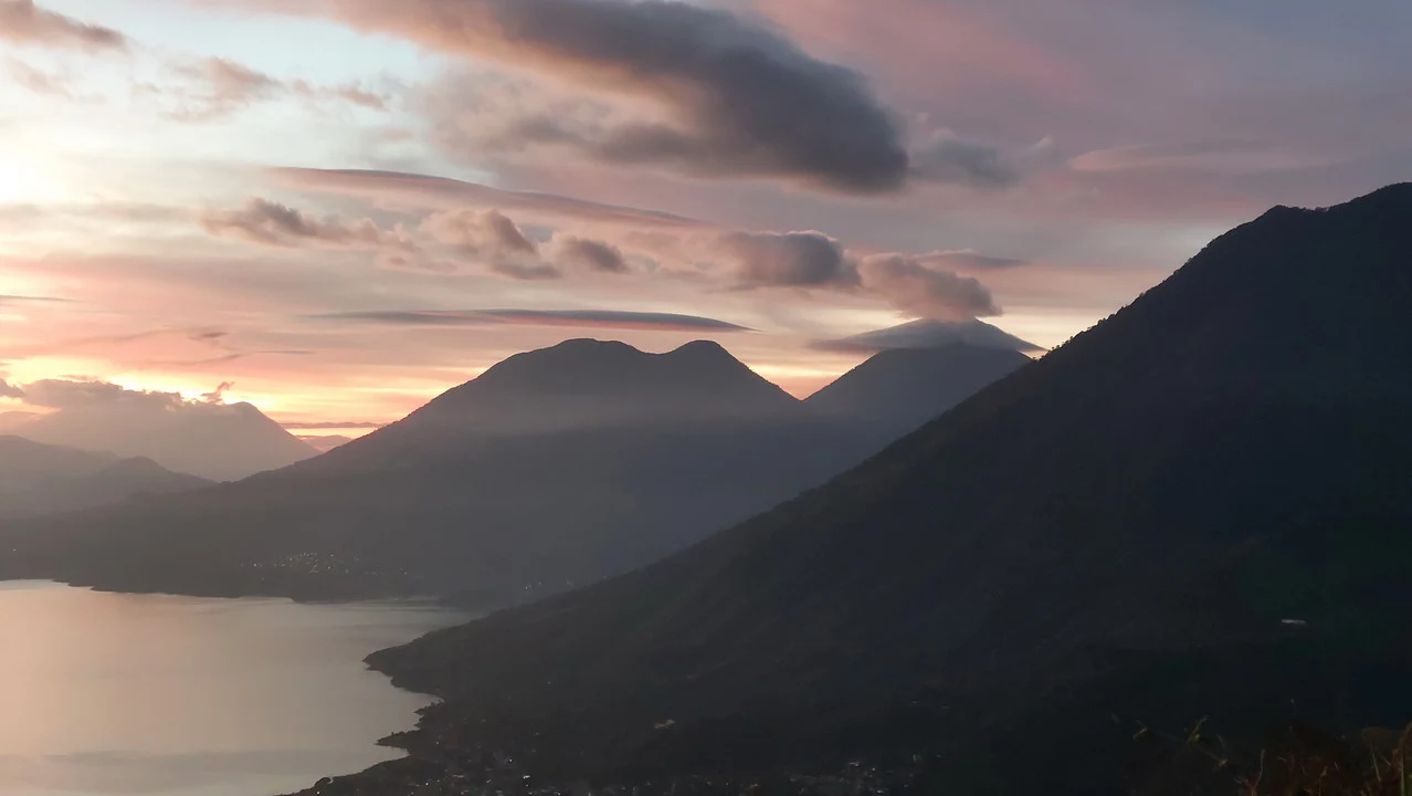 Alba sopra montagne e acqua con riflessi colorati.