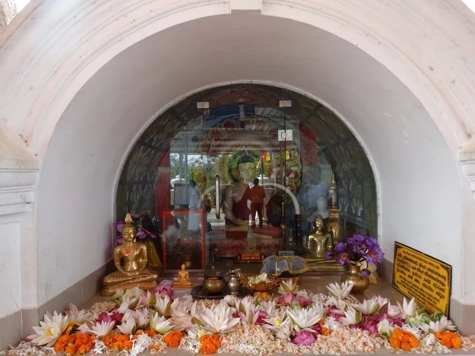 Interno di un santuario con statue di Buddha e offerte floreali.