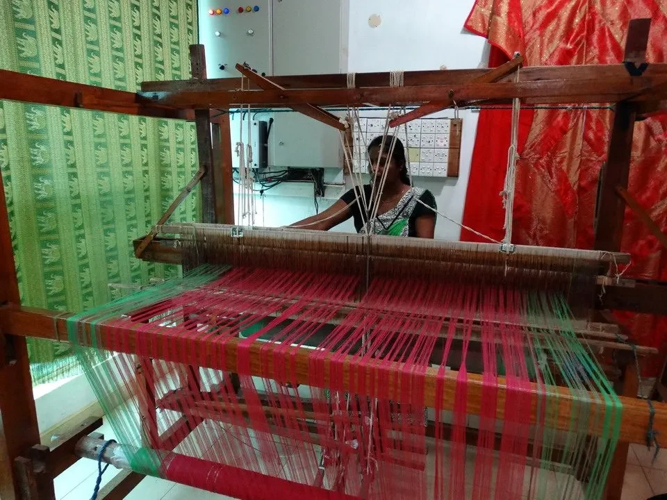 Artigiani stanno tessendo un tessuto colorato su un telaio tradizionale in Sri Lanka.