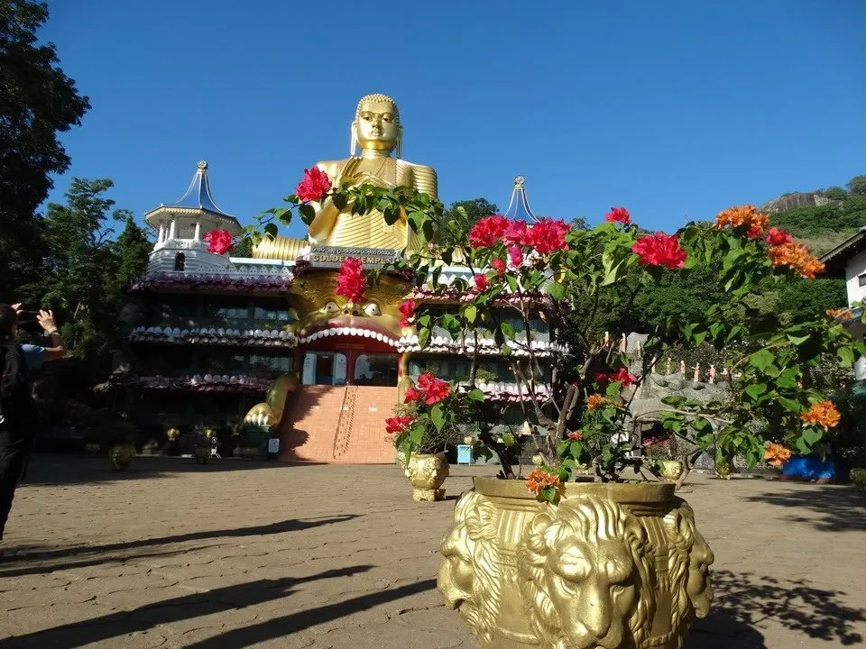 Statua del Buddha in un complesso templare adornato da fiori.