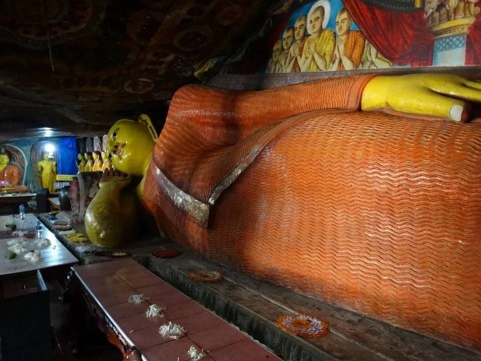 Interno di un tempio in Sri Lanka con grandi statue dorate e decorazioni murali.