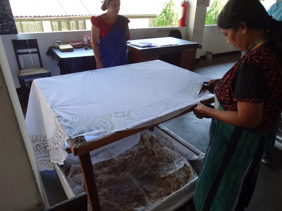 Due donne lavorano alla creazione di tessuto batik in un laboratorio artigianale.