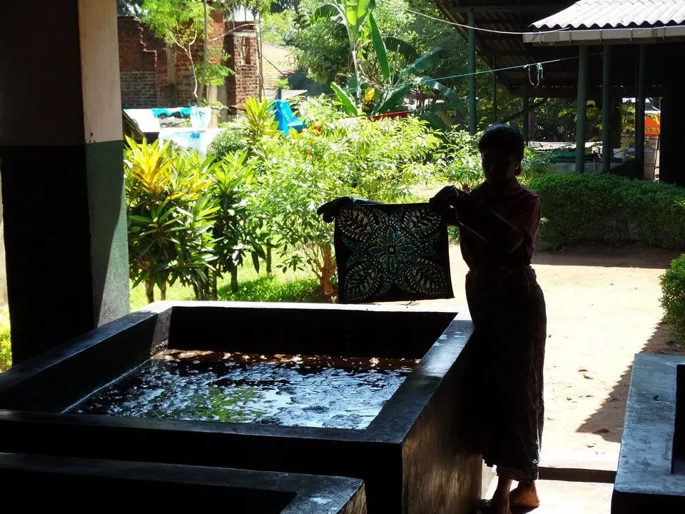 Una persona sta lavorando su un tessuto in una vasca d'acqua all'aperto.