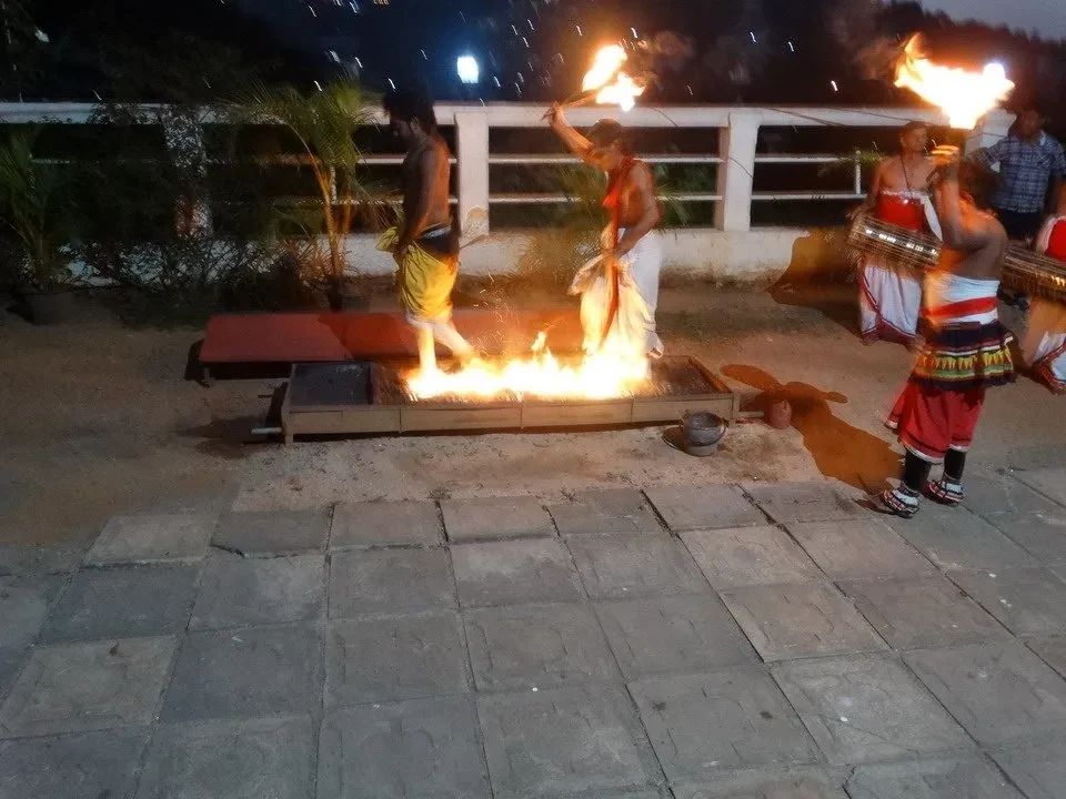 Danzatori eseguono una performance attorno a un fuoco notturno.