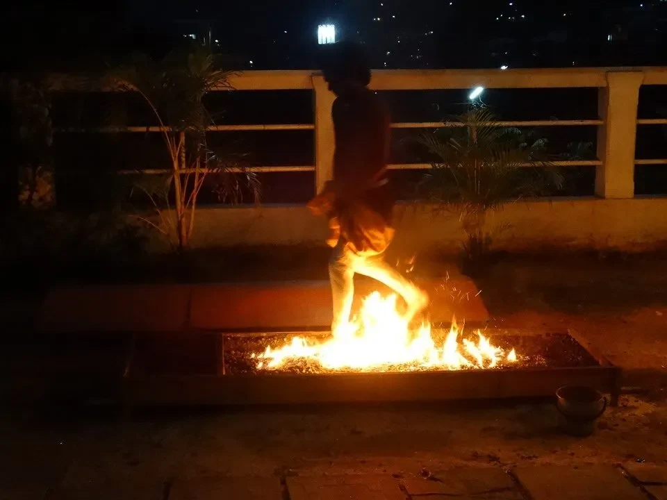 Una persona è in piedi vicino a un fuoco all'aperto di notte.