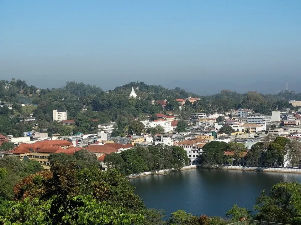 Vista panoramica di una città circondata da colline verdi e un corpo d'acqua.