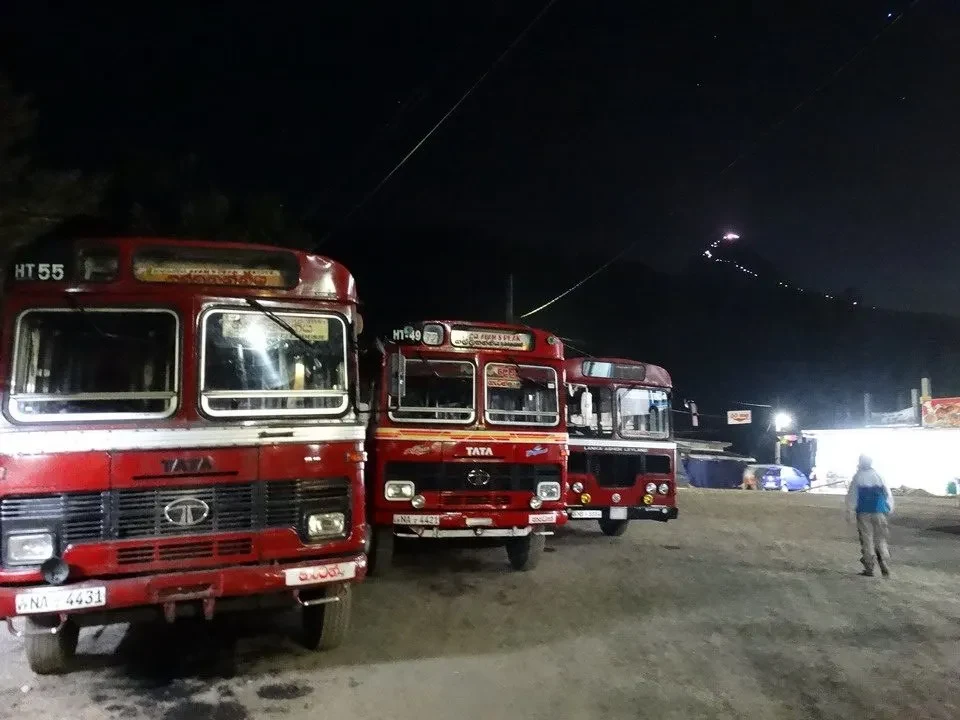 Un autobus rosso è parcheggiato in una zona rurale di Sri Lanka di notte.