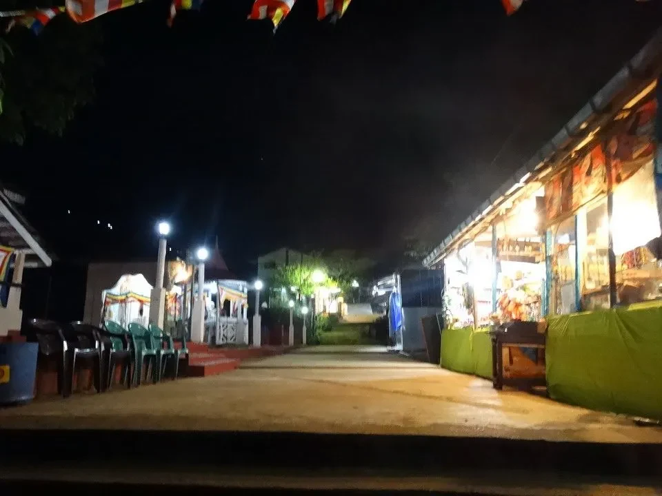 Percorso pedonale illuminato di notte con negozi lungo il lato.