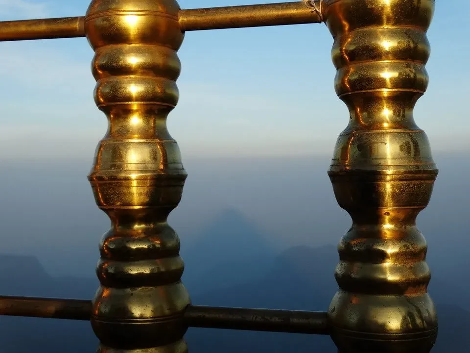 Ombra del triangolo della montagna visibile attraverso una ringhiera dorata.