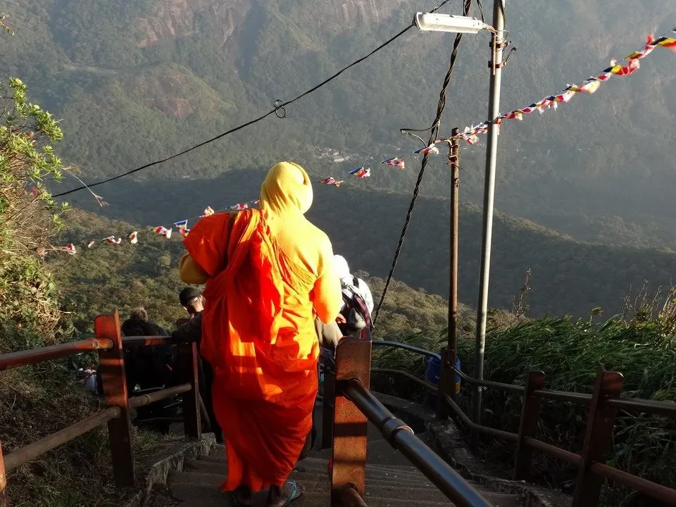 Un monaco cammina lungo un sentiero panoramico con vista sulle montagne in Sri Lanka.