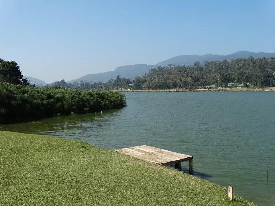 Un paesaggio sereno mostra un lago tranquillo con colline sullo sfondo in Sri Lanka.