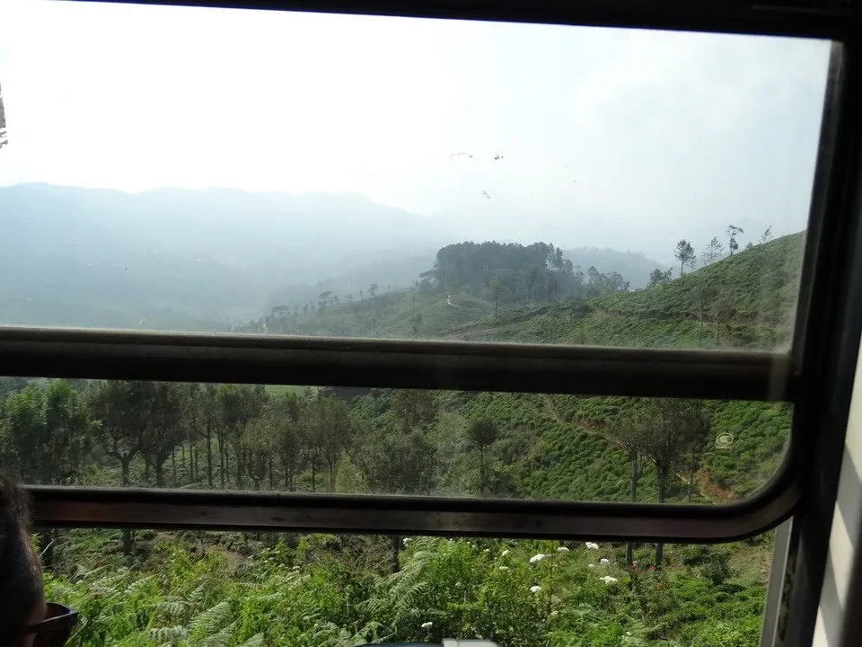 Paesaggio verde e collinare visto dalla finestra di un treno in Sri Lanka.