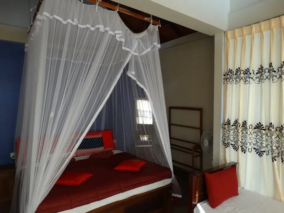 Interno di una camera da letto luminosa con tende bianche decorative.