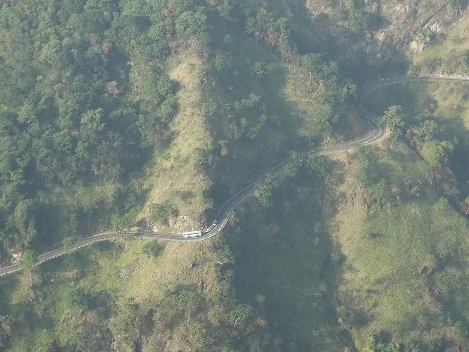 Una strada sinuosa attraversa un paesaggio collinare e boscoso in Sri Lanka.