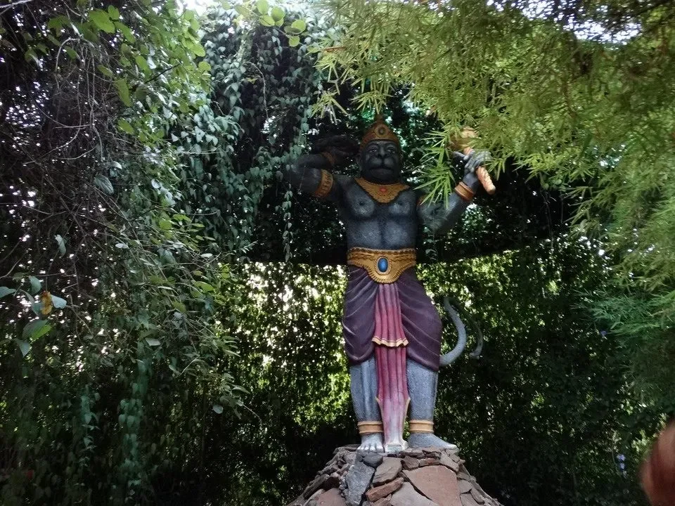 Statua di Buddha in un contesto naturale con vegetazione lussureggiante.