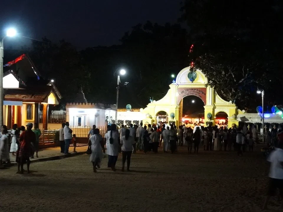 Una veduta notturna di un ingresso monumentale con persone in abiti tradizionali in Sri Lanka.