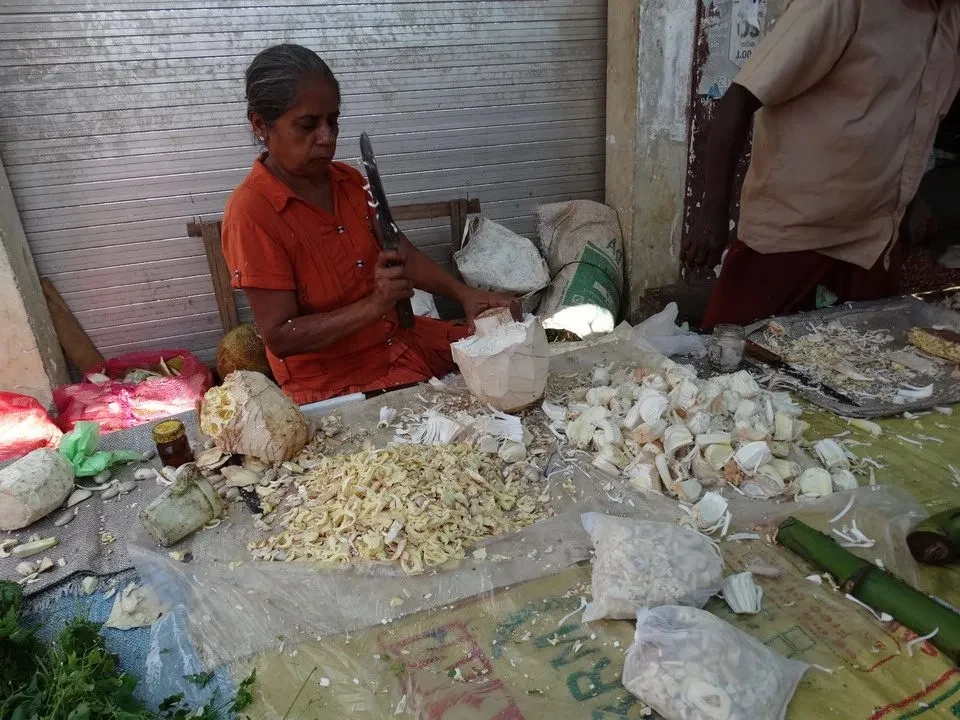 Una donna lavora con frutta e verdura in un mercato a Sri Lanka.