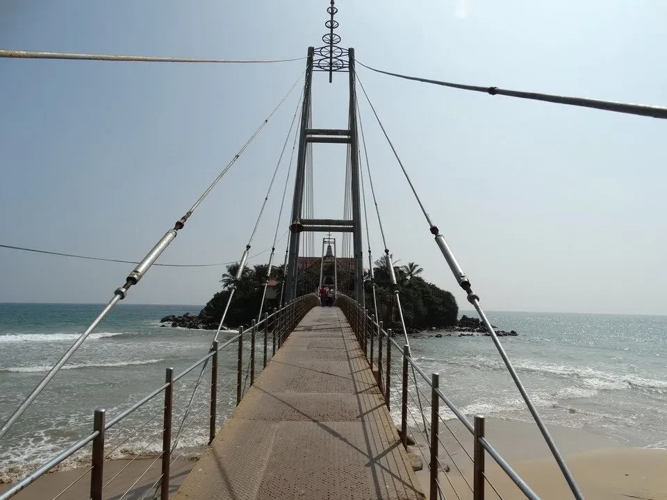 Ponte sospeso sopra una piccola isola rocciosa nel mare.