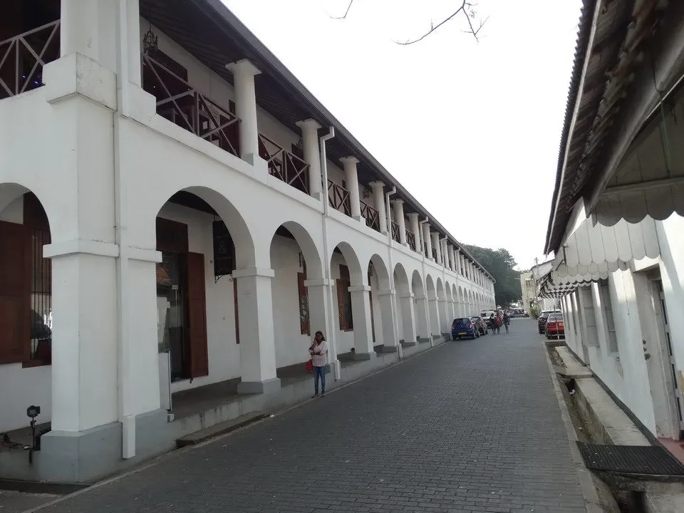 Una strada acciottolata fiancheggiata da edifici con archi bianchi si estende attraverso la città di Galle in Sri Lanka.