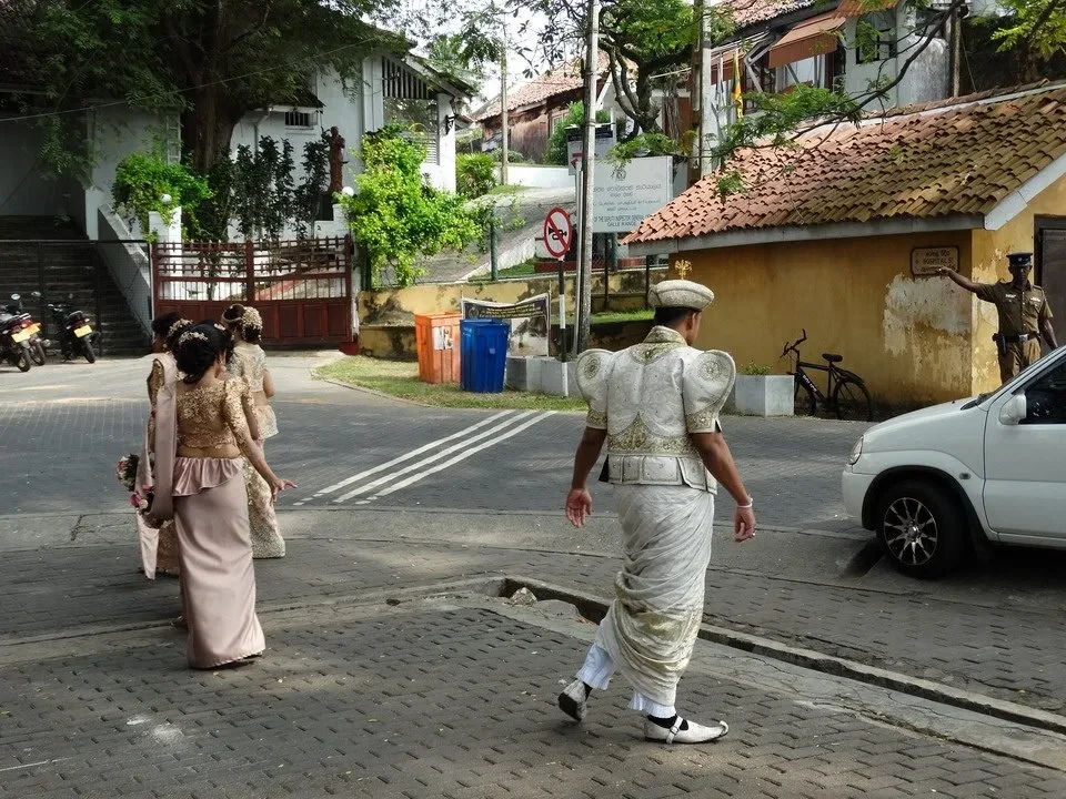 Uomini in abiti tradizionali camminano su una strada in un quartiere di Galle, Sri Lanka.