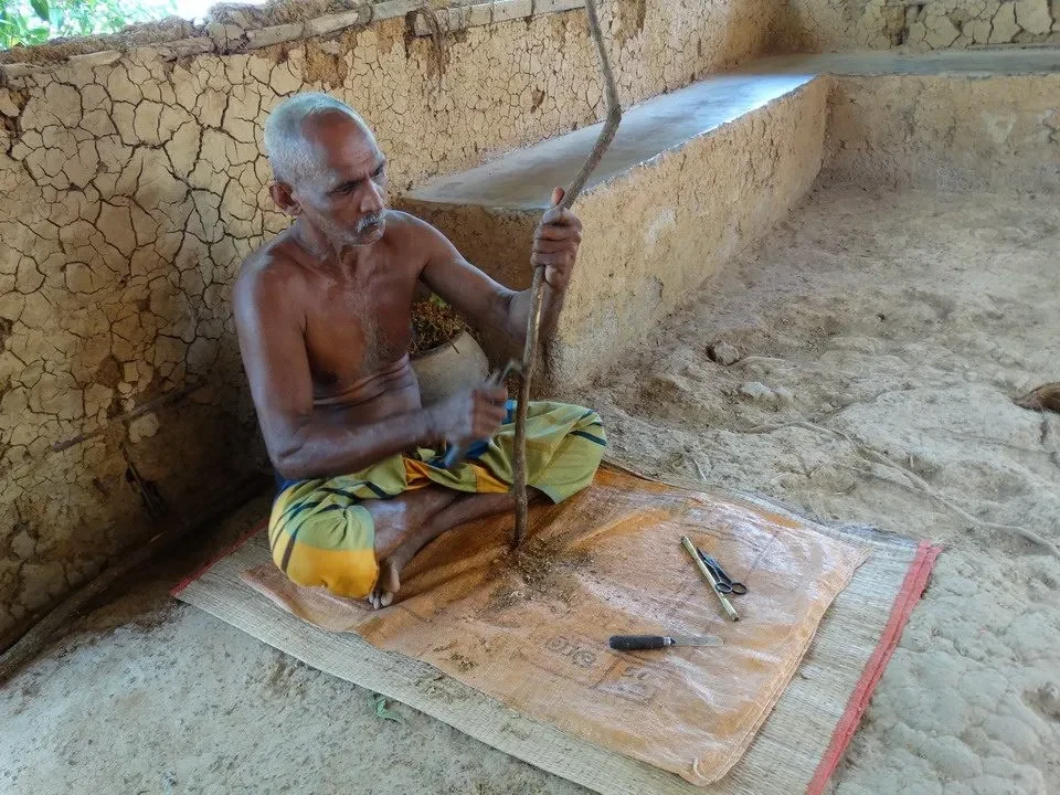 Un uomo si china per lavorare il legno in un ambiente rurale.
