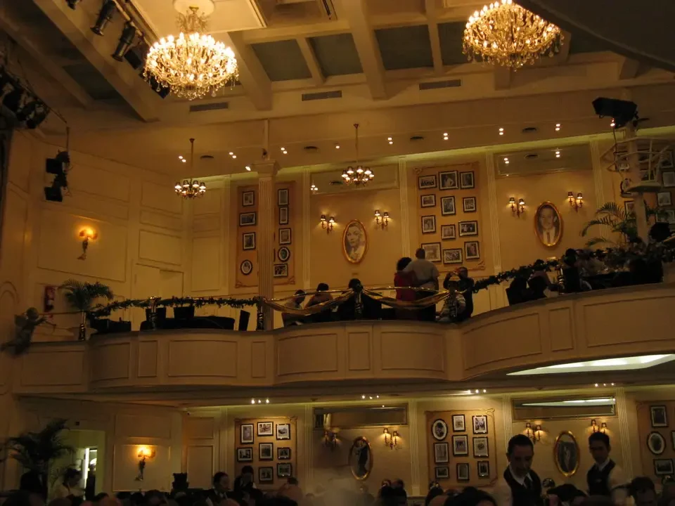 Una sala da ballo sontuosa con soffitti alti e balconi decorati ospita un evento elegante.