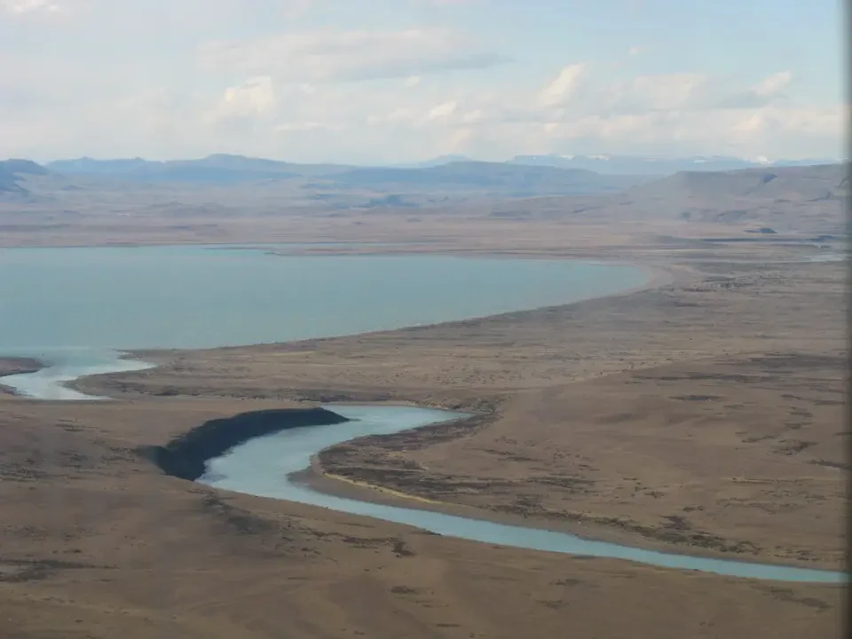 Un fiume serpeggia attraverso un vasto paesaggio patagonico con laghi e terre aride.