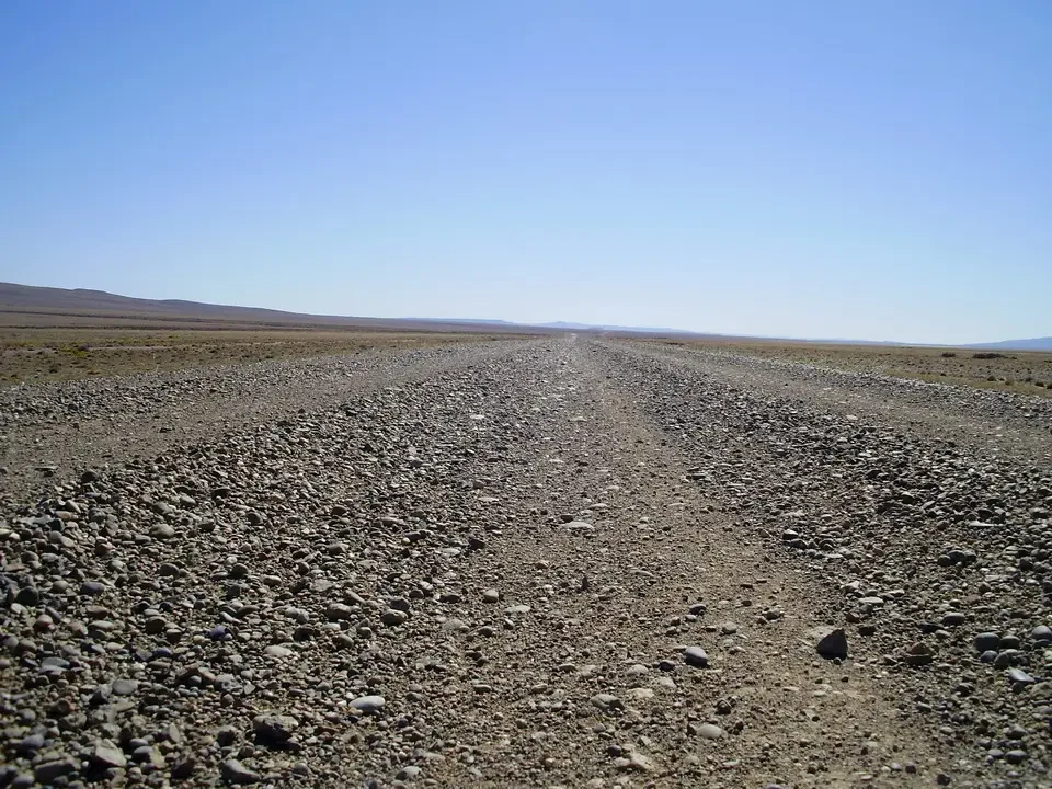 Una strada sterrata si estende verso l'orizzonte in un paesaggio patagonico.