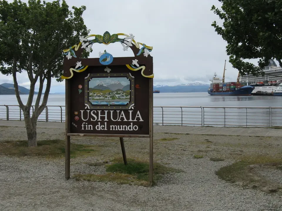 Panorama del lago Ushuaia con un cartello in primo piano e imbarcazioni sullo sfondo.