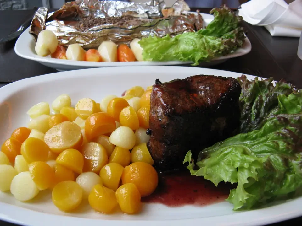 Un piatto di carne con contorno di verdure è presentato in un contesto patagonico.