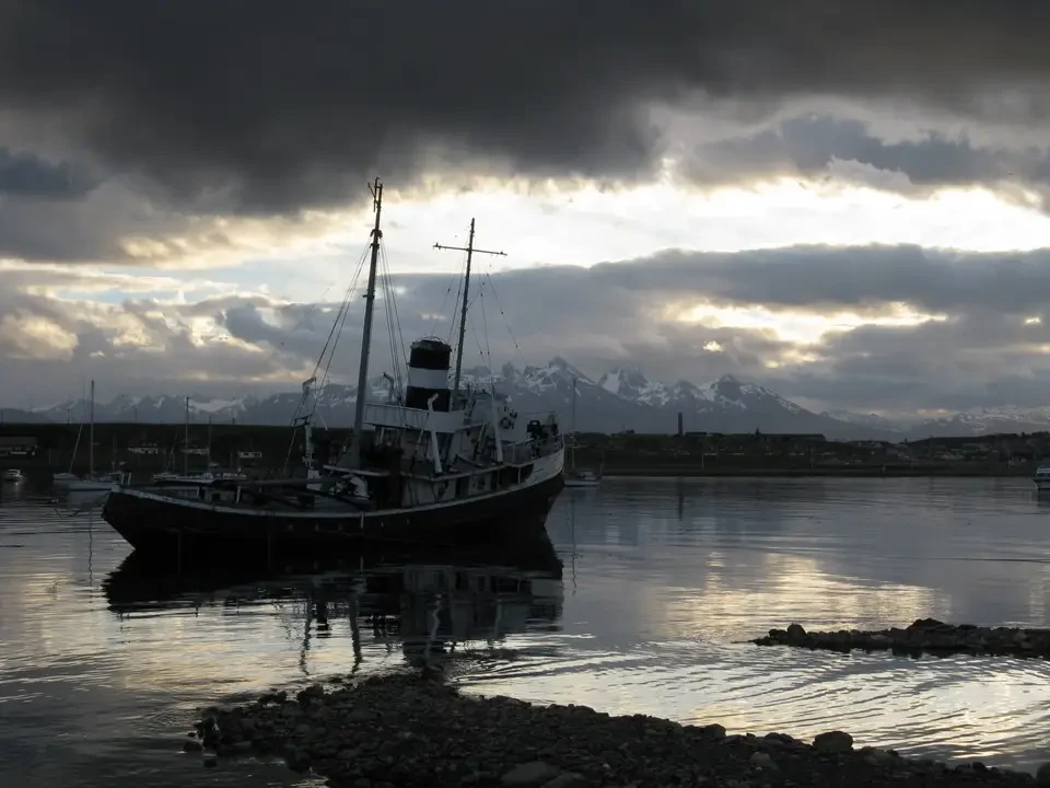 Barca tradizionale ormeggiata in una baia patagonica al tramonto.