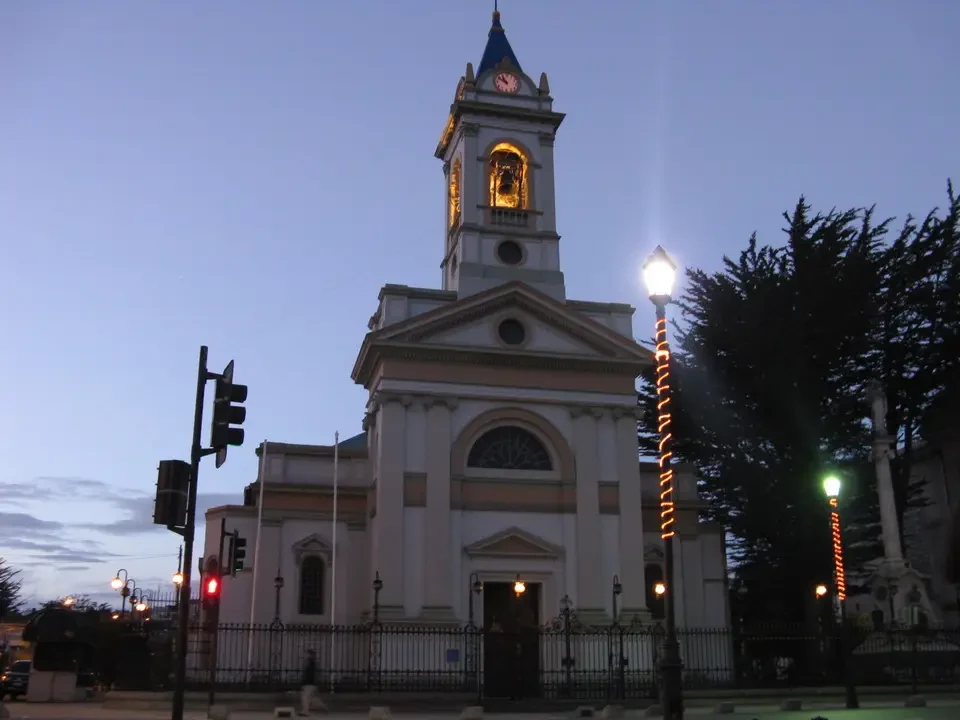 Chiesa storica bianca con campanile illuminato al tramonto.