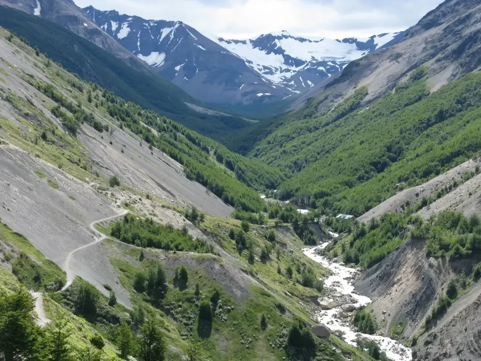 Valle profonda e selvaggia con pendii boscosi e un torrente che scorre attraverso il paesaggio montano patagonico.