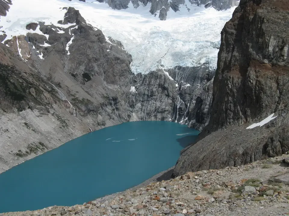 Un lago alpino glaciale incastonato tra montagne rocciose e ghiacciai.