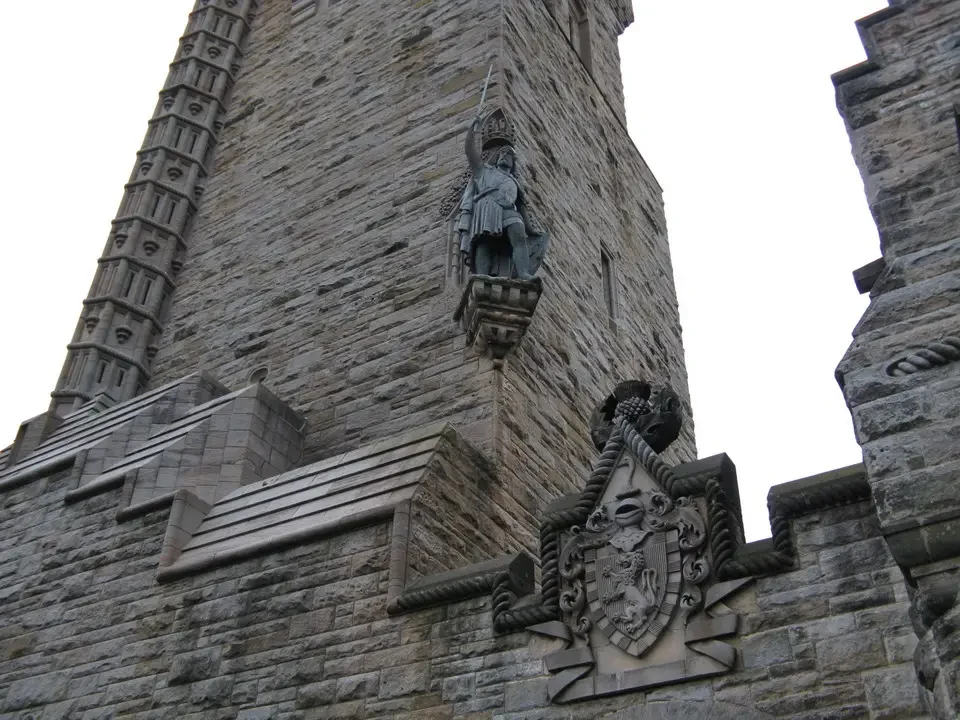 Una scultura in pietra è posizionata su una struttura muraria antica in Scozia.