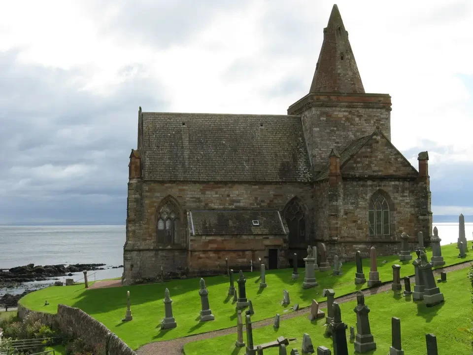 Chiesa storica in pietra con un cimitero circostante sulla costa scozzese.
