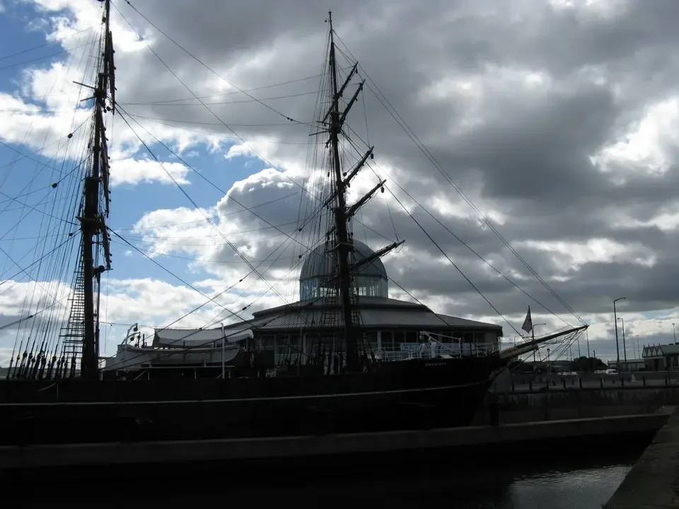 Una nave a vela ormeggiata in un porto scozzese sotto un cielo nuvoloso.