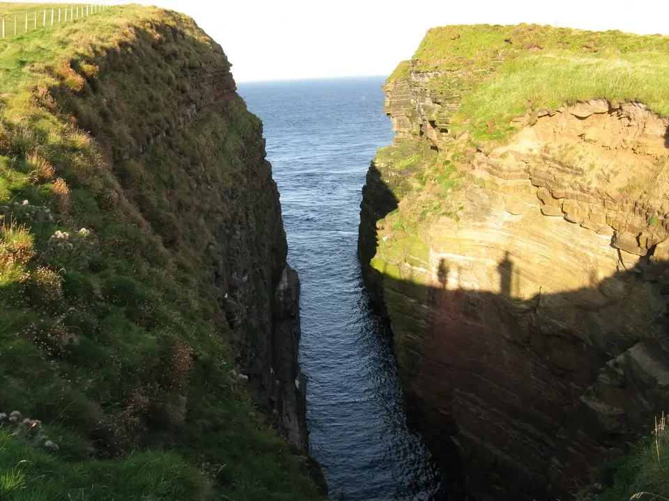 Una vista panoramica delle scogliere costiere della Scozia con un fiume che scorre tra di esse.