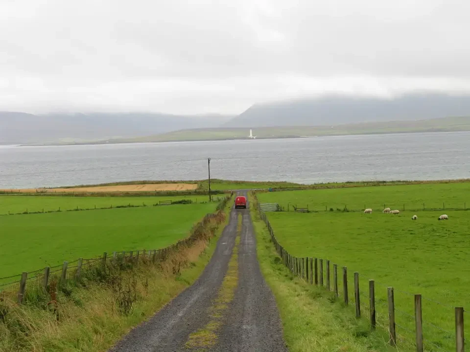Paesaggio rurale scozzese con una strada che costeggia un lago.