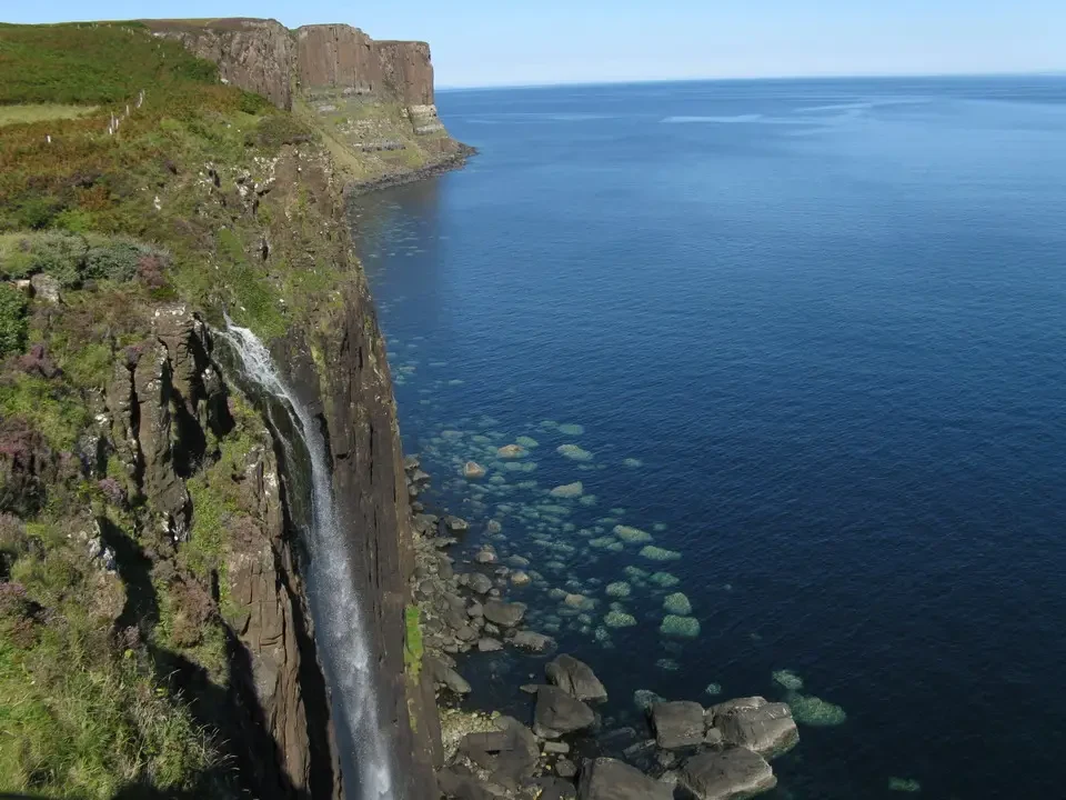 Una cascata scende lungo una scogliera rocciosa sulla costa della Scozia.
