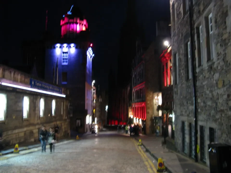 Una strada acciottolata illuminata di notte in Scozia con edifici storici.