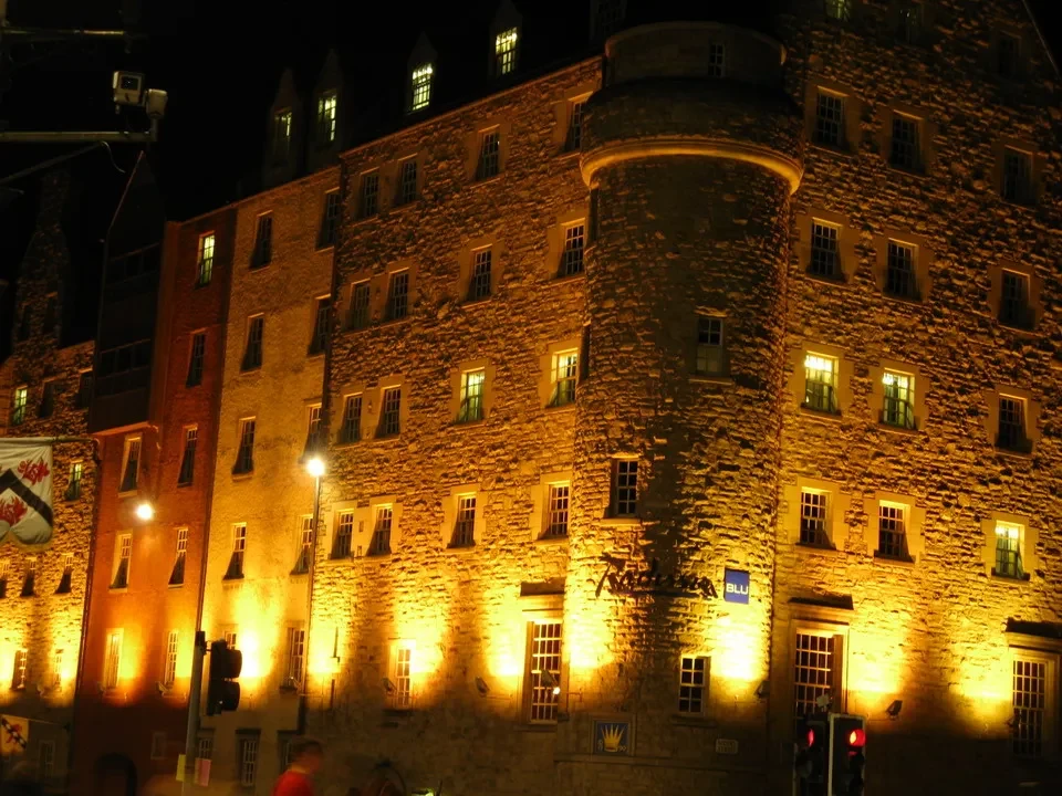 Vista notturna di un edificio storico in pietra con illuminazione calda.