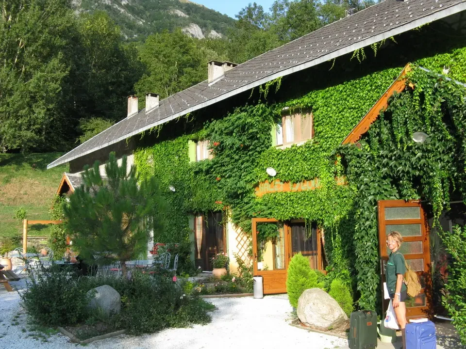 Una baita rustica ricoperta di edera si trova in un paesaggio montano.